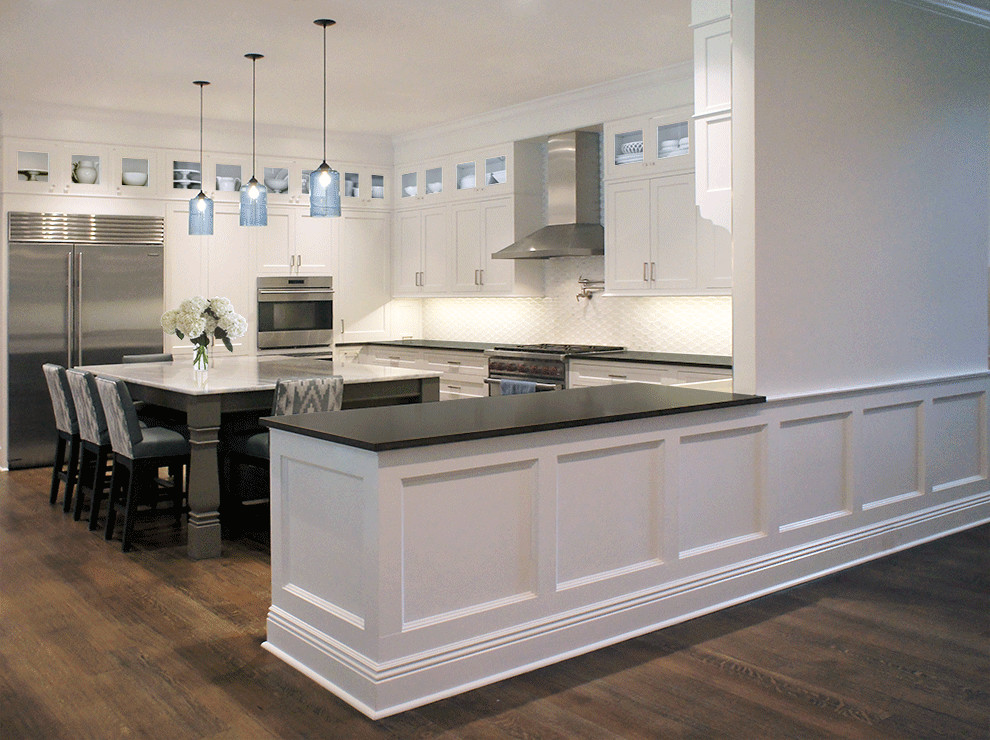 Exempel på ett mellanstort klassiskt kök, med en rustik diskho, luckor med upphöjd panel, vita skåp, granitbänkskiva, vitt stänkskydd, stänkskydd i tunnelbanekakel, rostfria vitvaror, mörkt trägolv och en köksö