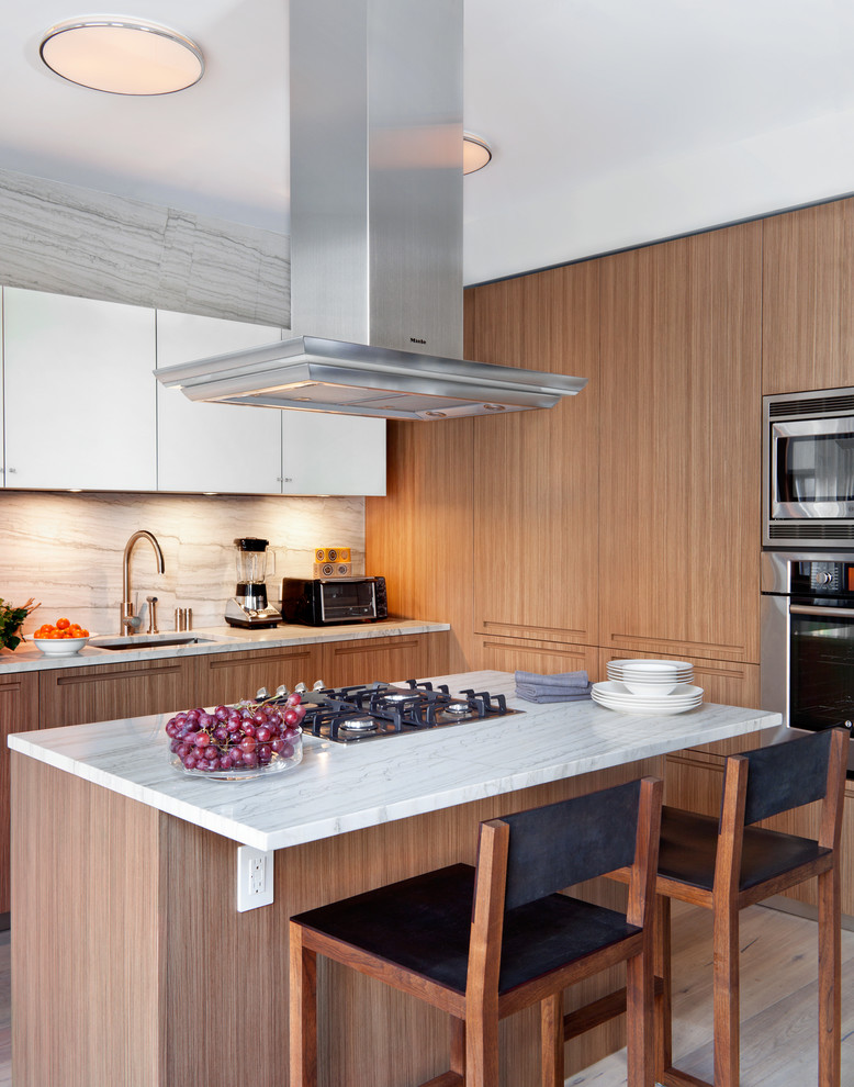 Moderne Küche mit hellbraunen Holzschränken, Küchengeräten aus Edelstahl, Unterbauwaschbecken, flächenbündigen Schrankfronten und Küchenrückwand in Weiß in New York