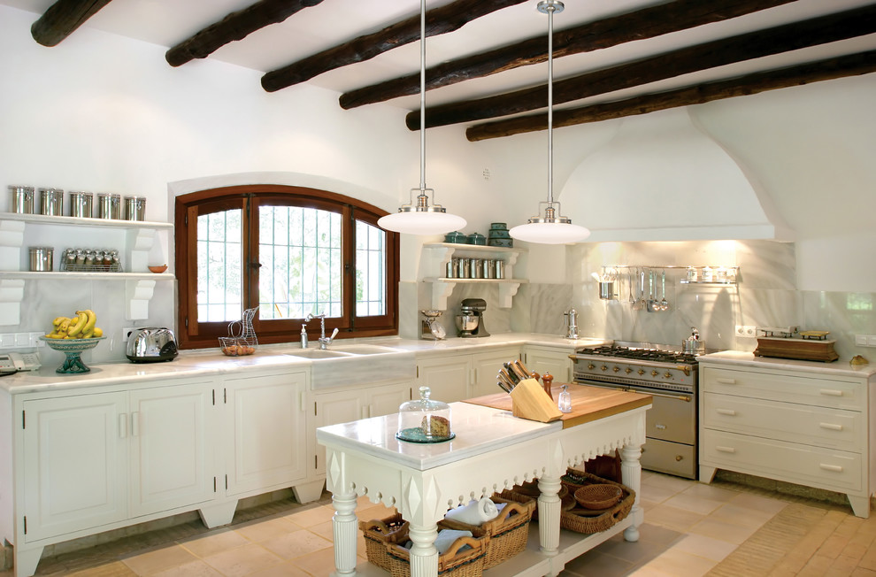 Inredning av ett lantligt l-kök, med en rustik diskho, luckor med upphöjd panel, vita skåp, grått stänkskydd, rostfria vitvaror och en köksö