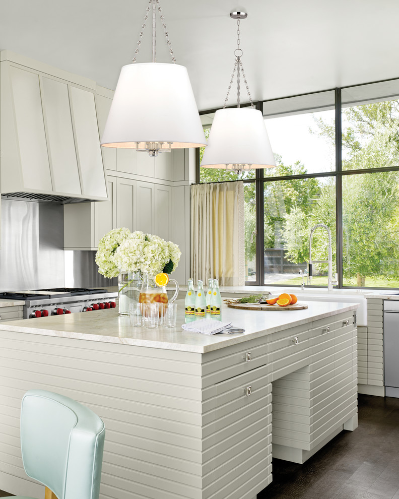 Example of a transitional l-shaped dark wood floor kitchen design in New York with a farmhouse sink, gray cabinets, metallic backsplash, stainless steel appliances and an island