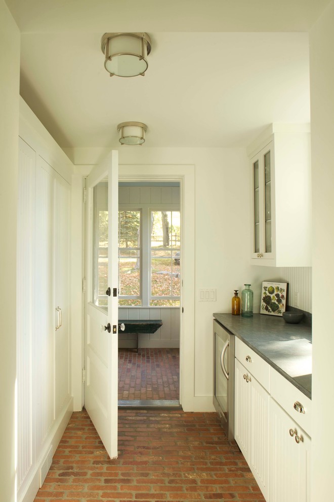 Klassische Küche mit weißen Schränken, Granit-Arbeitsplatte, Küchengeräten aus Edelstahl und Backsteinboden in New York
