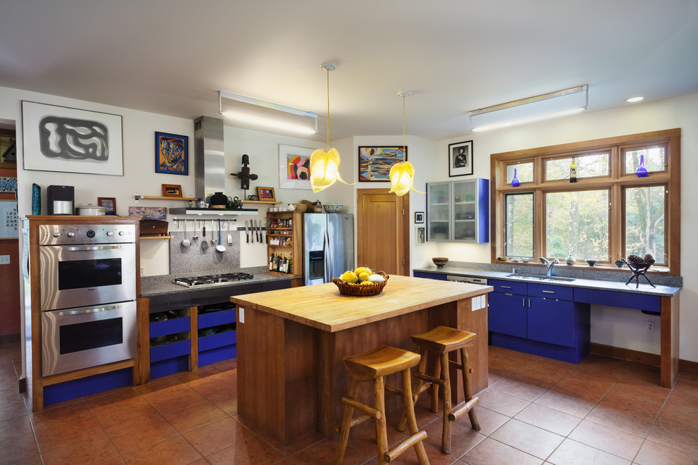 Пример оригинального дизайна: кухня в стиле фьюжн с врезной мойкой, плоскими фасадами, синими фасадами, техникой из нержавеющей стали, полом из терракотовой плитки, островом, оранжевым полом и мойкой у окна
