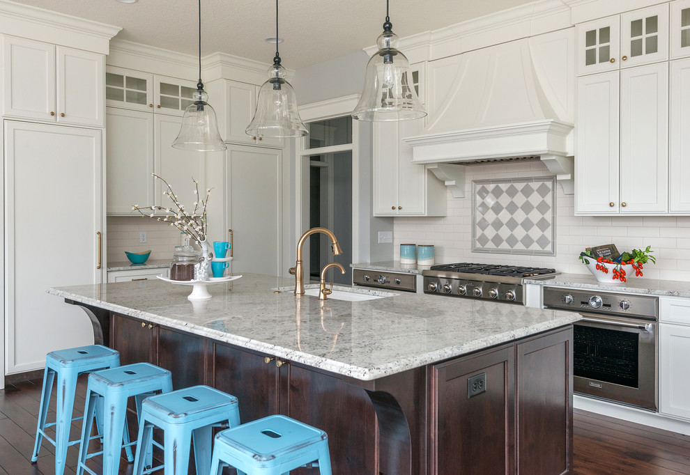 Exempel på ett klassiskt flerfärgad flerfärgat kök, med en undermonterad diskho, luckor med infälld panel, vita skåp, flerfärgad stänkskydd, rostfria vitvaror, mörkt trägolv, en köksö och brunt golv