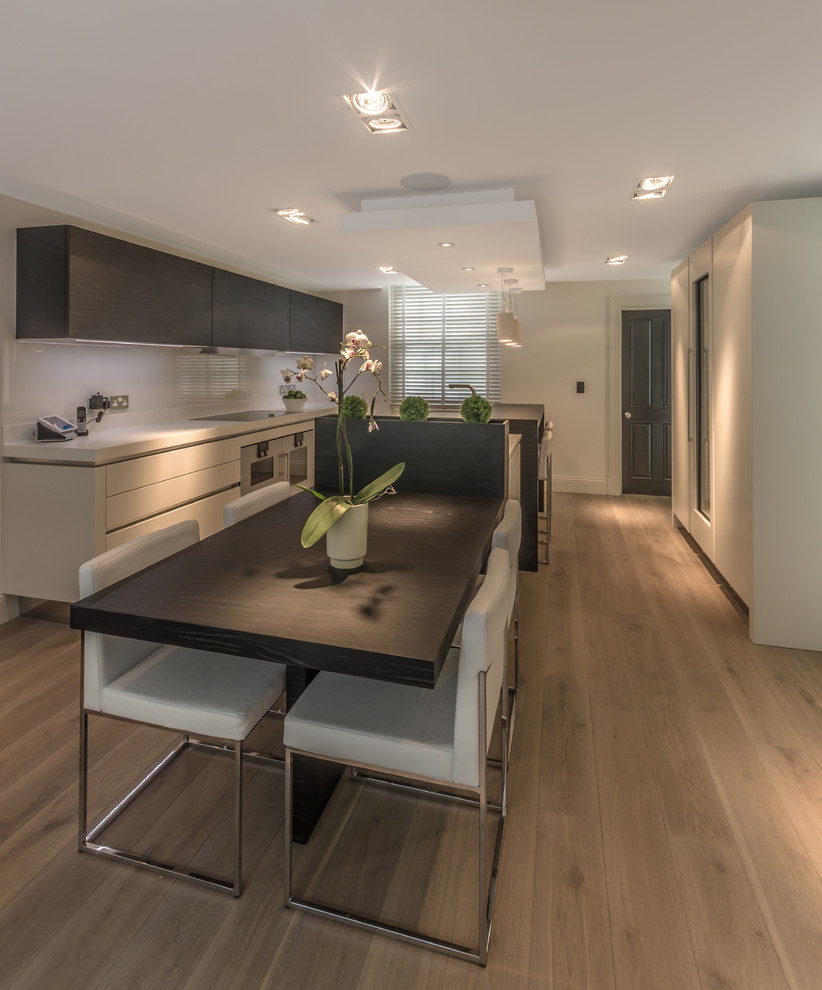 Example of a trendy galley light wood floor open concept kitchen design in Cheshire with dark wood cabinets, granite countertops, stainless steel appliances and an island