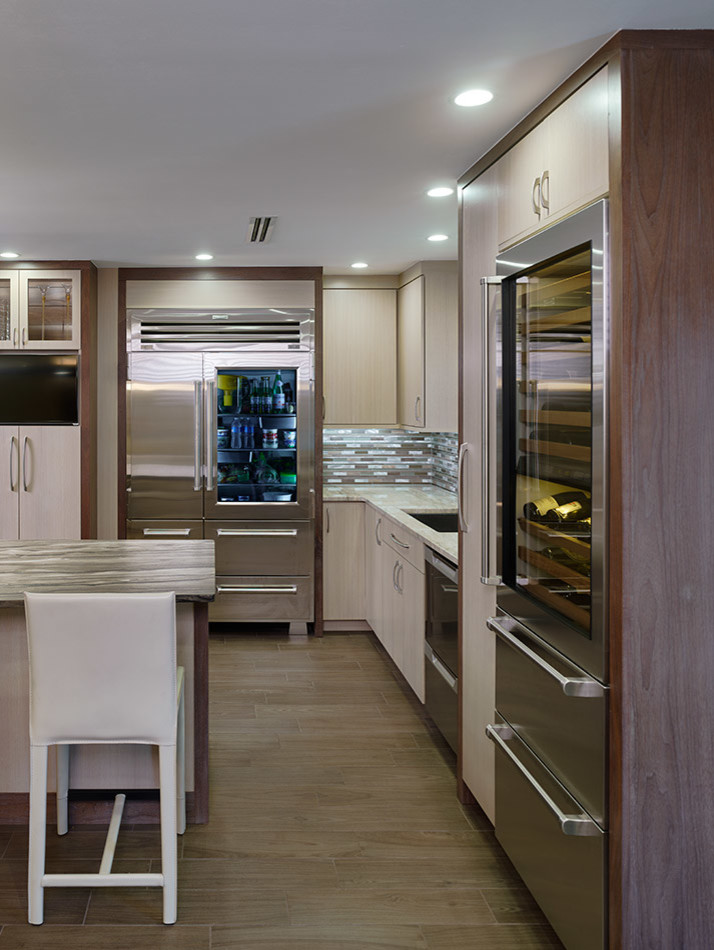 This is an example of a large contemporary u-shaped kitchen/diner in Philadelphia with a submerged sink, flat-panel cabinets, medium wood cabinets, granite worktops, metallic splashback, metal splashback, stainless steel appliances, porcelain flooring and an island.