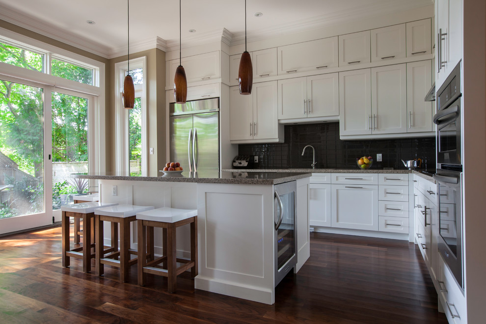 Modern inredning av ett mellanstort kök, med en undermonterad diskho, skåp i shakerstil, vita skåp, granitbänkskiva, grått stänkskydd, stänkskydd i glaskakel, rostfria vitvaror, mellanmörkt trägolv och en köksö