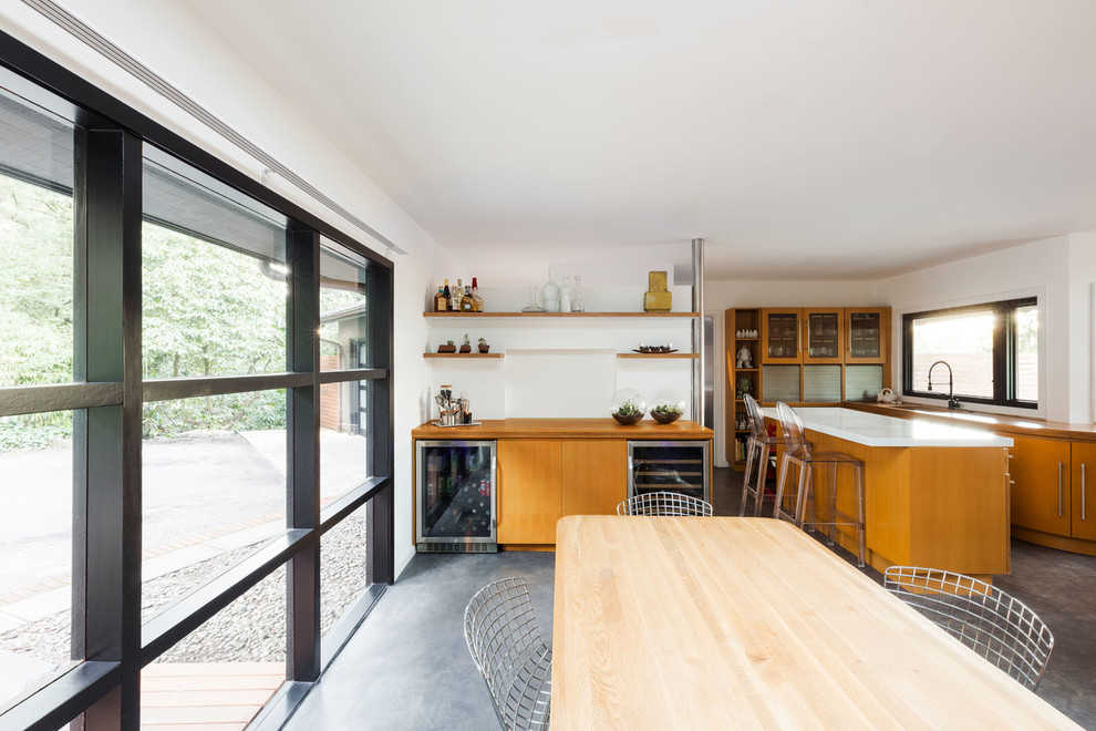 Immagine di una grande cucina minimalista chiusa con lavello sottopiano, ante lisce, ante in legno chiaro, top in legno, elettrodomestici in acciaio inossidabile, pavimento in cemento, pavimento grigio e top marrone
