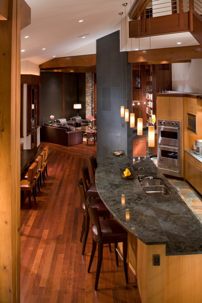 Zweizeilige, Mittelgroße Moderne Wohnküche mit Doppelwaschbecken, flächenbündigen Schrankfronten, hellen Holzschränken, Granit-Arbeitsplatte, Küchengeräten aus Edelstahl, braunem Holzboden und Kücheninsel in Denver