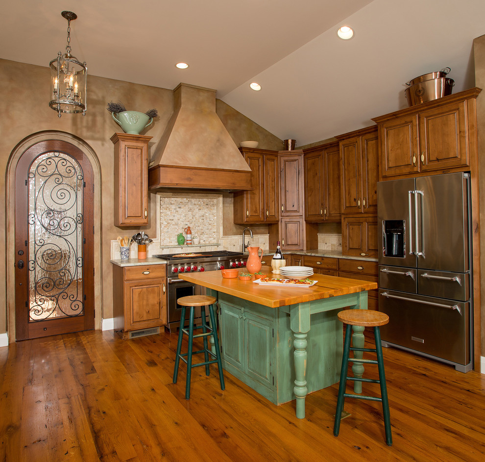 Inspiration for an eclectic l-shaped light wood floor and multicolored floor eat-in kitchen remodel in DC Metro with a farmhouse sink, raised-panel cabinets, distressed cabinets, granite countertops, beige backsplash, limestone backsplash, stainless steel appliances and an island