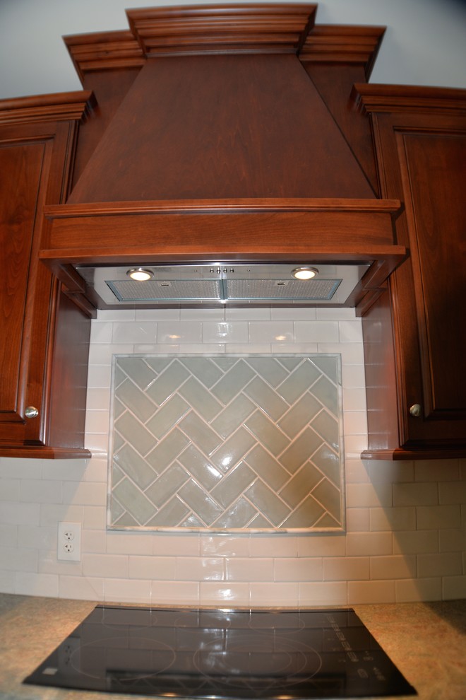 Klassisk inredning av ett mellanstort kök, med en undermonterad diskho, luckor med upphöjd panel, skåp i mellenmörkt trä, granitbänkskiva, beige stänkskydd, stänkskydd i tunnelbanekakel, rostfria vitvaror, klinkergolv i porslin och en köksö