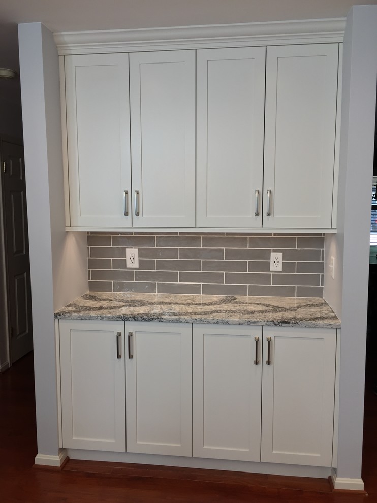 Example of a mid-sized transitional u-shaped medium tone wood floor and red floor open concept kitchen design in Baltimore with a double-bowl sink, shaker cabinets, white cabinets, quartz countertops, gray backsplash, ceramic backsplash, stainless steel appliances, no island and gray countertops
