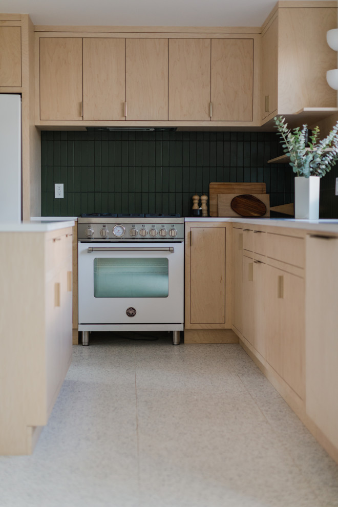 Example of a mid-sized danish l-shaped concrete floor and white floor open concept kitchen design in Los Angeles with beige cabinets, green backsplash, ceramic backsplash, white appliances, an island and white countertops