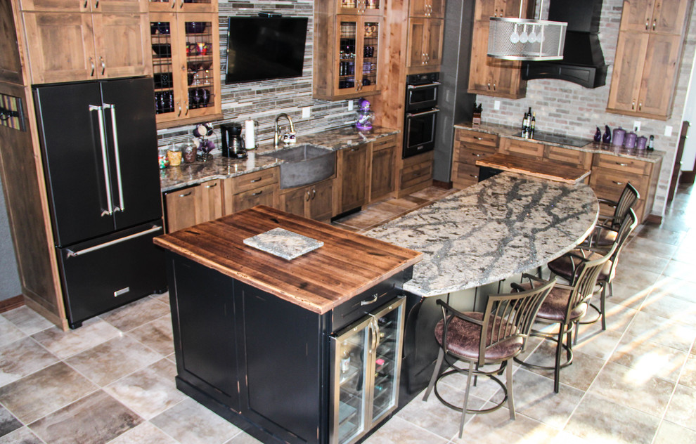 Example of a large mountain style l-shaped ceramic tile open concept kitchen design in Other with a farmhouse sink, shaker cabinets, medium tone wood cabinets, granite countertops, multicolored backsplash, matchstick tile backsplash, black appliances and an island