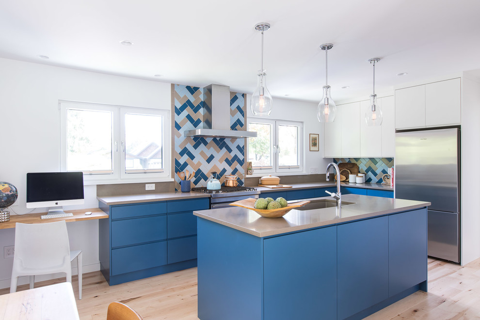 This is an example of a large contemporary l-shaped kitchen/diner in Vancouver with a submerged sink, flat-panel cabinets, blue cabinets, engineered stone countertops, multi-coloured splashback, ceramic splashback, stainless steel appliances, light hardwood flooring, an island and brown worktops.