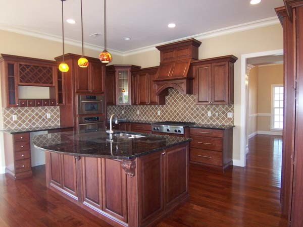 Exempel på ett mellanstort klassiskt l-kök, med en köksö, luckor med upphöjd panel, skåp i mellenmörkt trä, granitbänkskiva, beige stänkskydd, stänkskydd i stenkakel, rostfria vitvaror, en undermonterad diskho och mellanmörkt trägolv