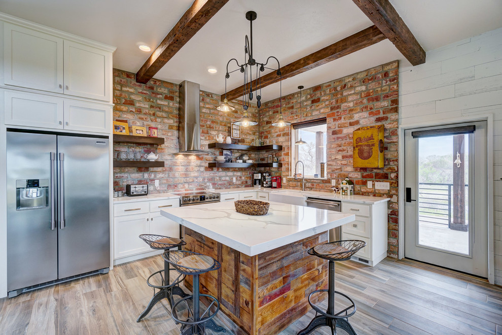 Rustik inredning av ett vit vitt l-kök, med en rustik diskho, skåp i shakerstil, vita skåp, rött stänkskydd, stänkskydd i tegel, rostfria vitvaror, mellanmörkt trägolv, en köksö och brunt golv