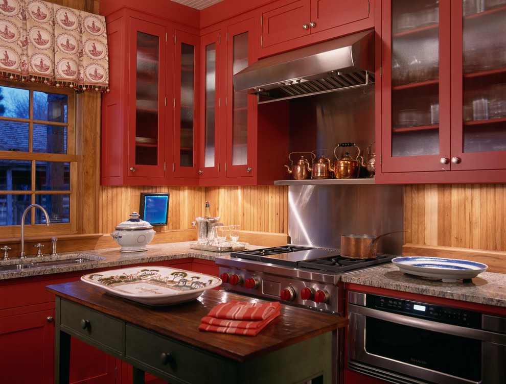 Réalisation d'une cuisine chalet avec un placard à porte vitrée, un électroménager en acier inoxydable, un plan de travail en granite et des portes de placard rouges.