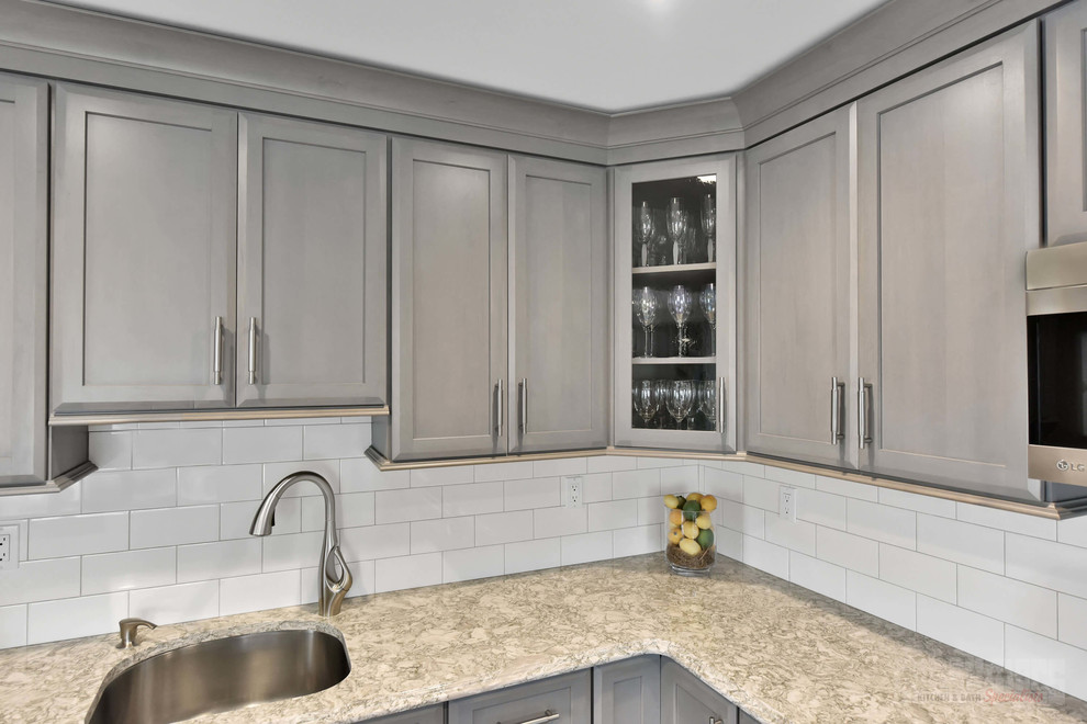 Inspiration for a large l-shaped eat-in kitchen remodel in New York with an undermount sink, shaker cabinets, gray cabinets, quartz countertops, white backsplash, stainless steel appliances, an island and white countertops