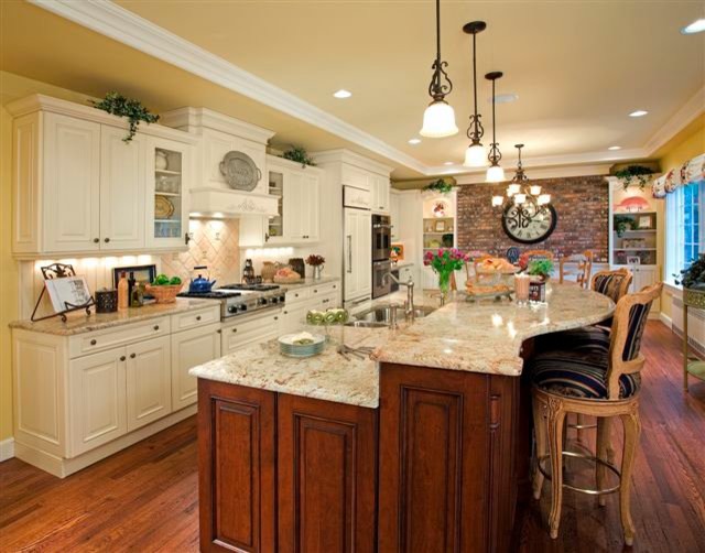 Example of a classic l-shaped medium tone wood floor eat-in kitchen design in New York with a double-bowl sink, raised-panel cabinets, white cabinets, granite countertops, beige backsplash, stone tile backsplash, paneled appliances and an island