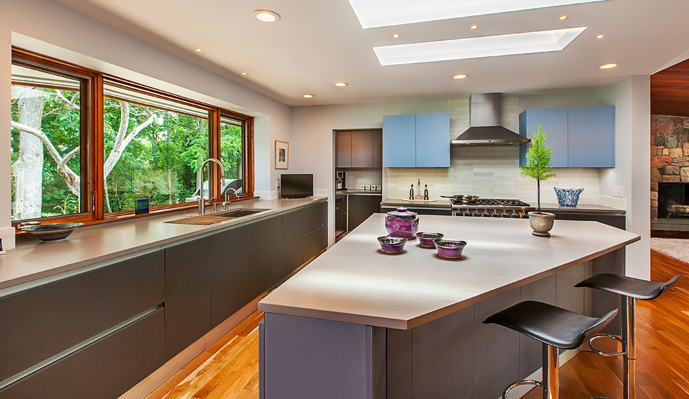 Foto på ett funkis kök, med en undermonterad diskho, släta luckor, blå skåp, beige stänkskydd, rostfria vitvaror, mellanmörkt trägolv, en köksö och bänkskiva i koppar