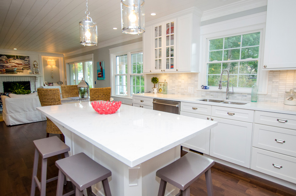 Inspiration for a mid-sized coastal single-wall dark wood floor open concept kitchen remodel in Cleveland with a double-bowl sink, recessed-panel cabinets, white cabinets, white backsplash, stone tile backsplash, stainless steel appliances and an island
