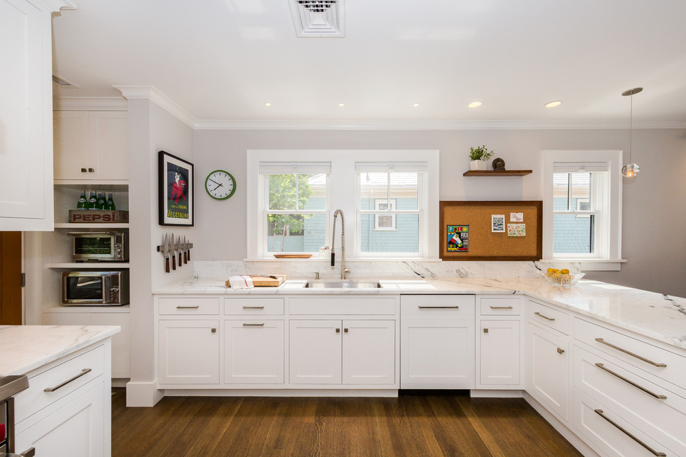 Bild på ett mellanstort vintage vit vitt kök, med en undermonterad diskho, skåp i shakerstil, vita skåp, marmorbänkskiva, grått stänkskydd, stänkskydd i cementkakel, rostfria vitvaror, mörkt trägolv, en halv köksö och brunt golv