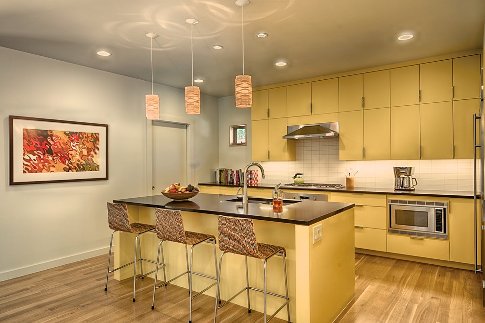 Example of a trendy u-shaped enclosed kitchen design in Dallas with a double-bowl sink, flat-panel cabinets, yellow cabinets, white backsplash and stainless steel appliances
