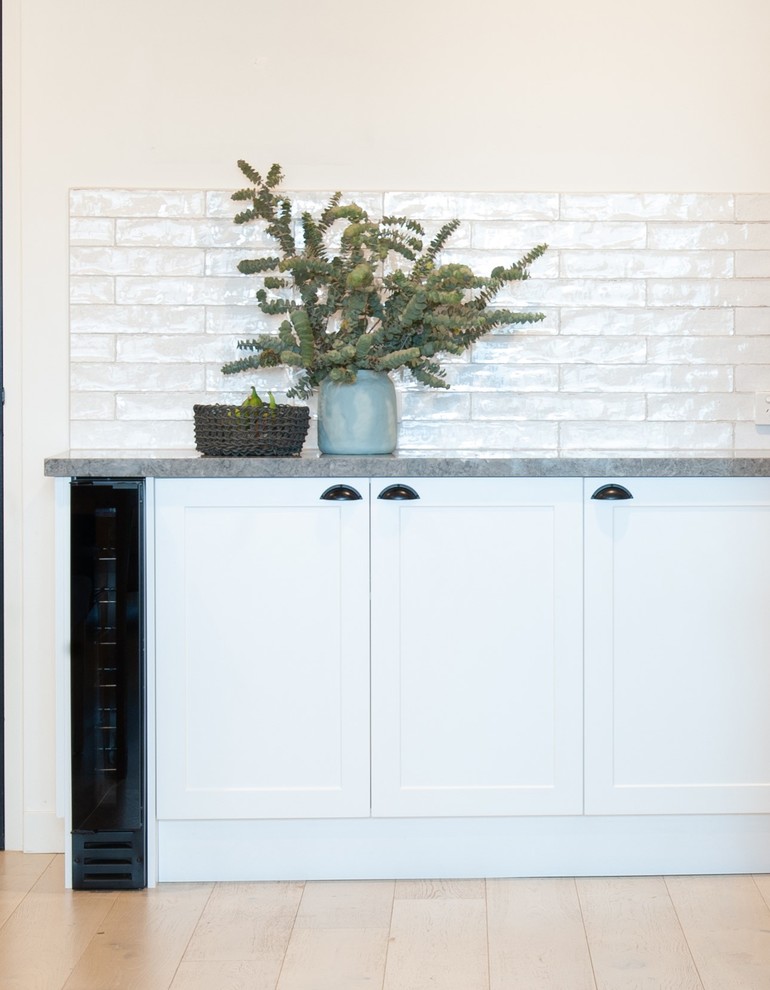 Idéer för att renovera ett litet funkis grå grått l-kök, med en dubbel diskho, luckor med infälld panel, vita skåp, laminatbänkskiva, vitt stänkskydd, stänkskydd i tunnelbanekakel, rostfria vitvaror, ljust trägolv och en köksö
