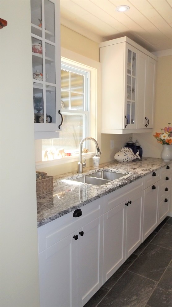 Example of a small arts and crafts galley porcelain tile and gray floor enclosed kitchen design in Other with a double-bowl sink, shaker cabinets, white cabinets, granite countertops, stainless steel appliances and no island