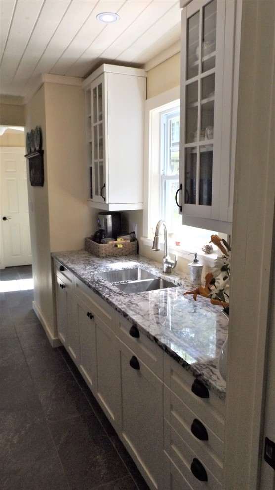 Small arts and crafts galley porcelain tile and gray floor enclosed kitchen photo in Other with a double-bowl sink, shaker cabinets, white cabinets, granite countertops, stainless steel appliances and no island