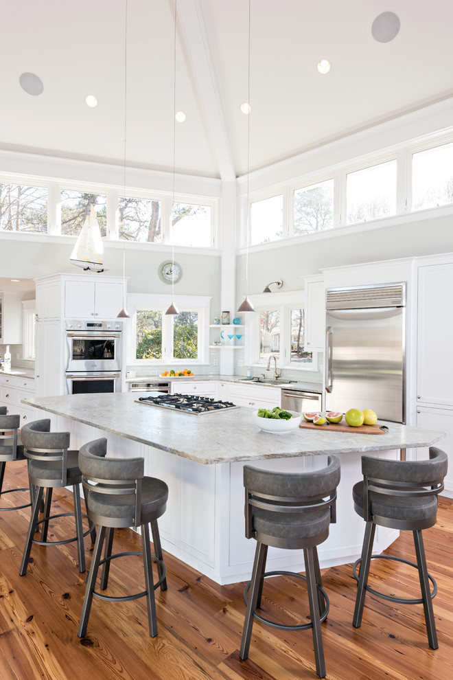 Foto di un cucina con isola centrale stile marino con ante in stile shaker, ante bianche, elettrodomestici in acciaio inossidabile e parquet chiaro