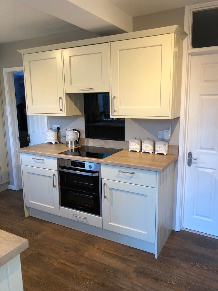 Photo of a rural kitchen in Berkshire with shaker cabinets, laminate countertops and black splashback.