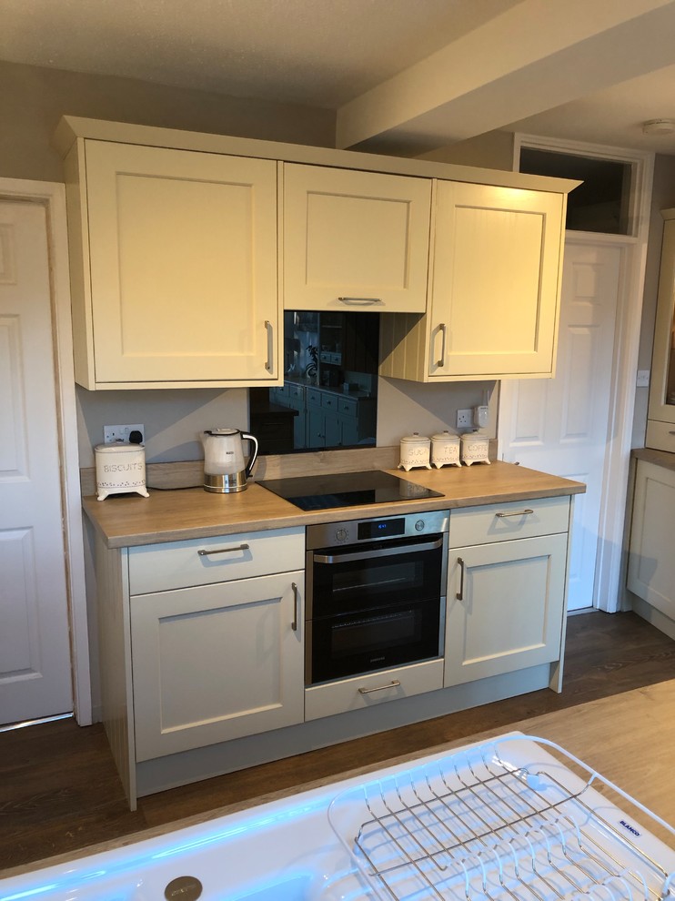 This is an example of a rural kitchen in Oxfordshire with shaker cabinets, laminate countertops and black splashback.