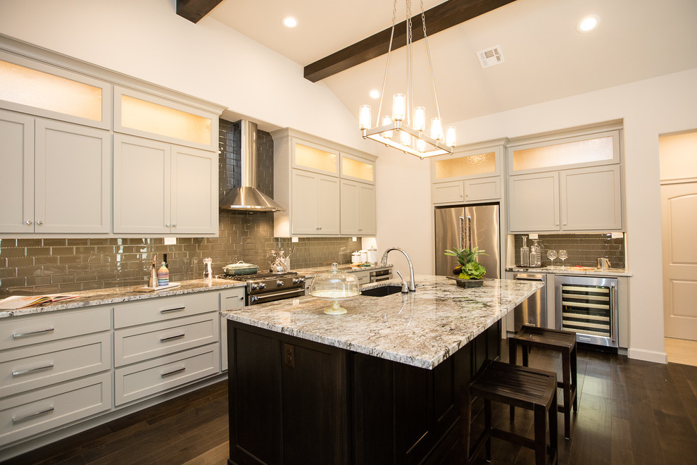 Inspiration for a large transitional l-shaped dark wood floor and brown floor kitchen remodel in Other with an undermount sink, shaker cabinets, beige cabinets, granite countertops, multicolored backsplash, glass tile backsplash, stainless steel appliances, an island and multicolored countertops