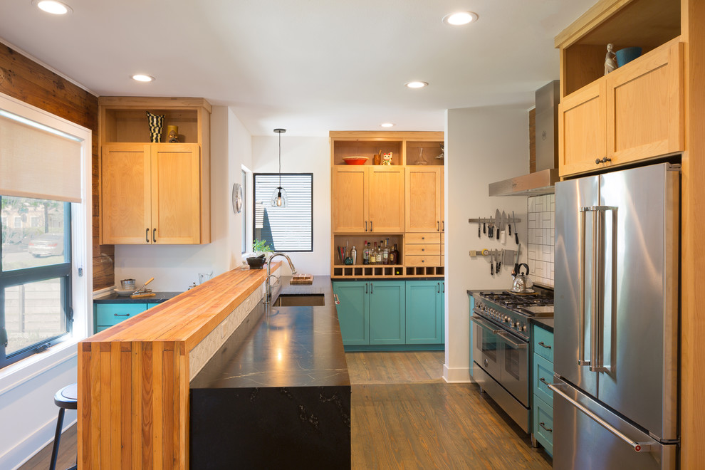 Example of a mid-sized transitional galley medium tone wood floor open concept kitchen design in Austin with an undermount sink, recessed-panel cabinets, turquoise cabinets, soapstone countertops, beige backsplash, ceramic backsplash, stainless steel appliances and a peninsula