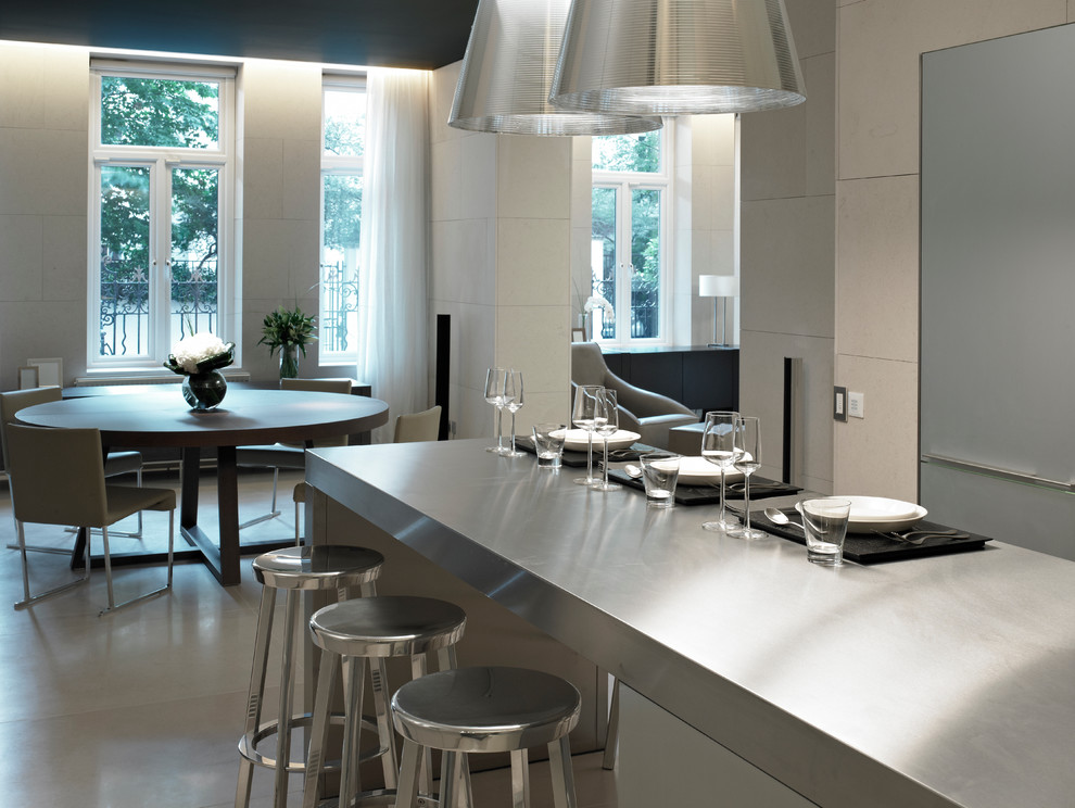 This is an example of a medium sized contemporary u-shaped open plan kitchen in London with flat-panel cabinets, an island, a double-bowl sink, grey cabinets, granite worktops, metallic splashback, metal splashback, stainless steel appliances and limestone flooring.