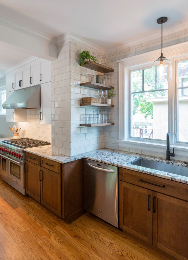 Example of a mid-sized classic medium tone wood floor and brown floor open concept kitchen design in Cincinnati with an undermount sink, recessed-panel cabinets, medium tone wood cabinets, white backsplash, ceramic backsplash, stainless steel appliances and an island