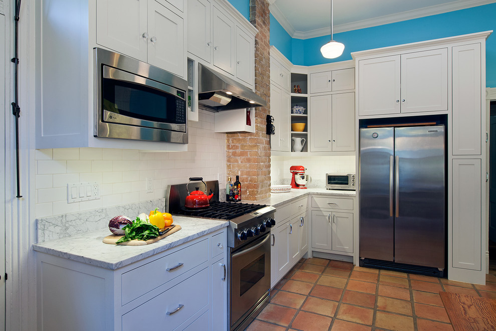 Immagine di una cucina classica con lavello stile country, ante lisce, ante bianche, top in marmo, paraspruzzi blu, elettrodomestici in acciaio inossidabile e pavimento in terracotta