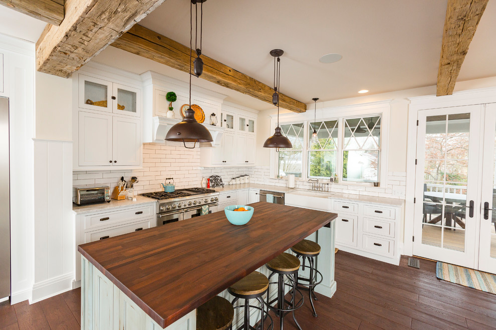 Example of a large cottage l-shaped dark wood floor and brown floor eat-in kitchen design in Cincinnati with a farmhouse sink, white cabinets, white backsplash, stainless steel appliances, an island, marble countertops, beaded inset cabinets and porcelain backsplash