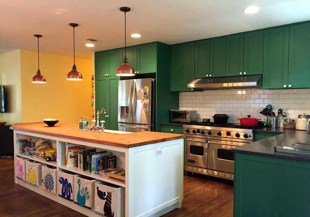 オースティンにある高級な広いコンテンポラリースタイルのおしゃれなキッチン (サブウェイタイルのキッチンパネル、シルバーの調理設備、無垢フローリング、エプロンフロントシンク、シェーカースタイル扉のキャビネット、緑のキャビネット、木材カウンター、白いキッチンパネル、茶色い床) の写真