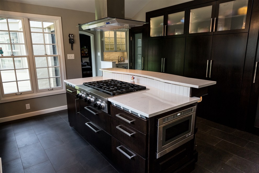 Bild på ett mellanstort funkis kök, med skåp i mörkt trä, vitt stänkskydd, rostfria vitvaror, en köksö, en undermonterad diskho, luckor med upphöjd panel, skiffergolv, marmorbänkskiva, stänkskydd i stenkakel och grått golv