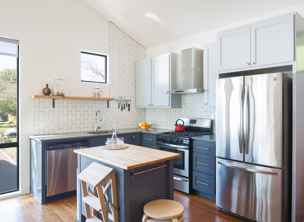 Kitchen - small transitional l-shaped medium tone wood floor and orange floor kitchen idea in Austin with an undermount sink, soapstone countertops, white backsplash, subway tile backsplash, stainless steel appliances, an island, shaker cabinets and blue cabinets