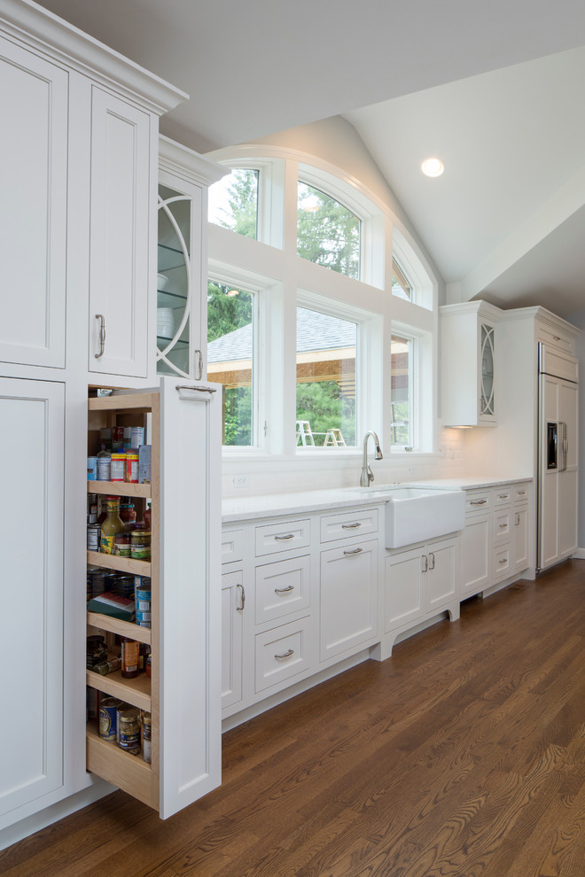 Photo of an expansive traditional u-shaped kitchen/diner in Cincinnati with an integrated sink, flat-panel cabinets, white cabinets, engineered stone countertops, white splashback, cement tile splashback, white appliances and medium hardwood flooring.