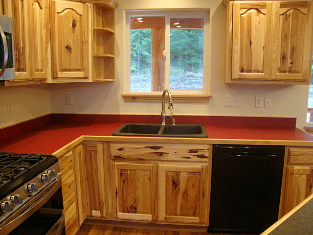 Inredning av ett rustikt mellanstort kök, med laminatbänkskiva, rött stänkskydd, en köksö, en dubbel diskho, luckor med upphöjd panel, skåp i ljust trä, rostfria vitvaror, mellanmörkt trägolv och brunt golv