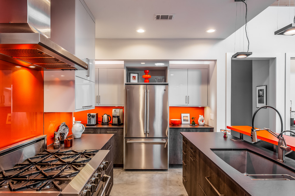 Inspiration for a mid-sized contemporary u-shaped concrete floor and gray floor eat-in kitchen remodel in New Orleans with a single-bowl sink, flat-panel cabinets, dark wood cabinets, quartz countertops, orange backsplash, glass tile backsplash, stainless steel appliances, an island and black countertops