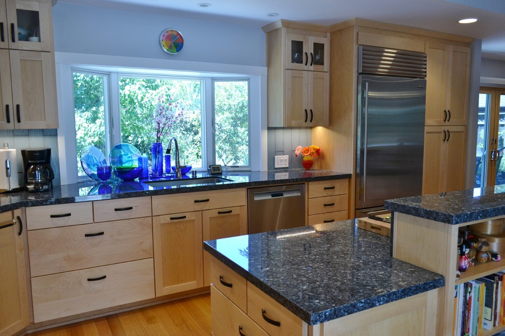 Inredning av ett modernt stort kök, med en undermonterad diskho, luckor med upphöjd panel, skåp i ljust trä, granitbänkskiva, blått stänkskydd, stänkskydd i glaskakel, rostfria vitvaror, mellanmörkt trägolv, en köksö och brunt golv