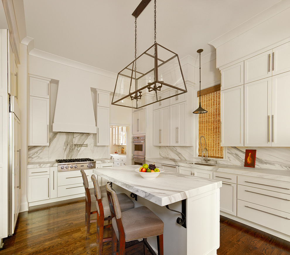 Traditional kitchen in Charleston with shaker cabinets, integrated appliances, white splashback and stone slab splashback.