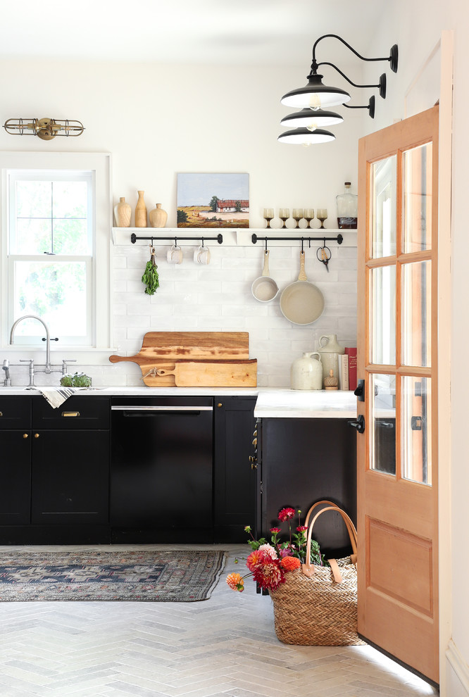 Imagen de cocina de estilo de casa de campo con armarios estilo shaker, puertas de armario negras, salpicadero verde, electrodomésticos negros, suelo gris y encimeras blancas