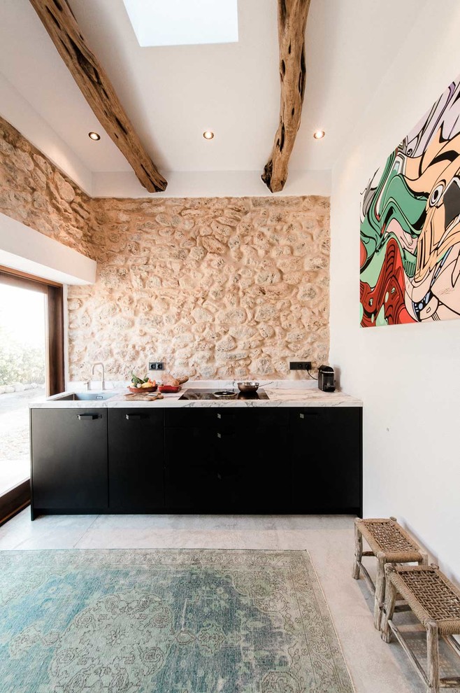 Foto de cocina lineal mediterránea pequeña abierta sin isla con armarios con paneles lisos, puertas de armario negras, salpicadero beige y suelo de cemento