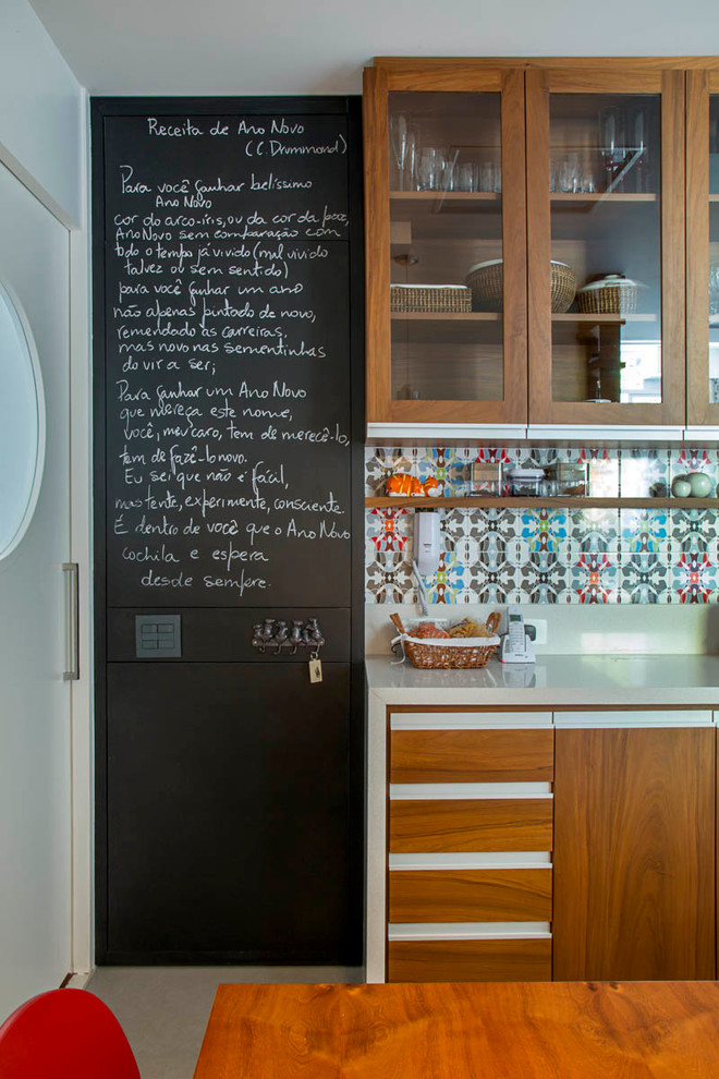 Modern inredning av ett kök, med flerfärgad stänkskydd och luckor med glaspanel
